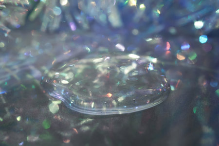 A drop of serum in tinsel in a Christmas theme in purple shades in dark tones.