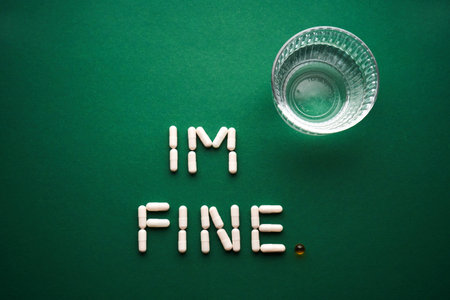 Capsules formed into the inscription Im fine on a green background with a glass of water.の写真素材