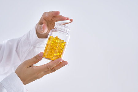 A hand holds a jar of OMEGA 3 capsules.の写真素材