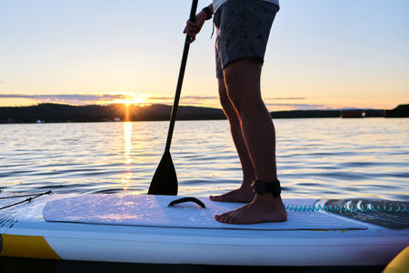 Male legs on a paddle board.