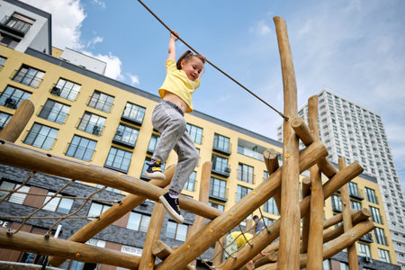 A girl hangs on a rope from a wooden sports complex.の写真素材