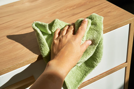 A womans hand wipes the chest of drawers with a rag.の写真素材