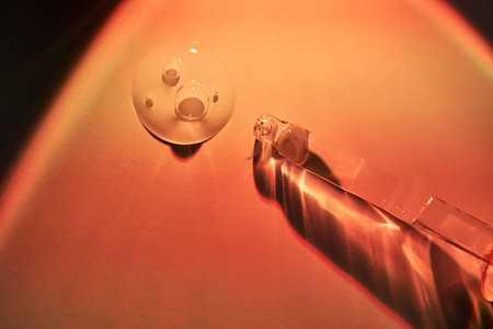 A dropper and a drop of sunscreen body serum in the orange sunset light.の写真素材