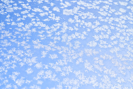 Abstract winter background. Frost on a frozen window against the blue sky.の写真素材