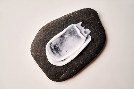 A smear of white cream on a black stone.の写真素材