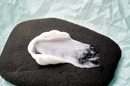 A smear of white cream on a black stone.の写真素材