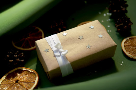 Christmas gift in craft paper on a green background.