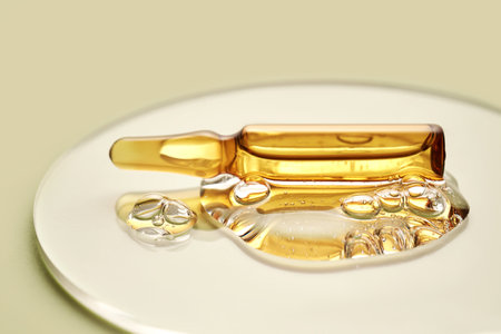 Ampoule in a drop of cosmetic gel on a green background.の写真素材