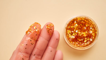 Cosmetic gel with glitter on womens fingers on a beige background.の写真素材