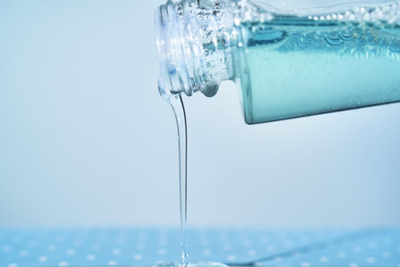 Cosmetic bottle from which serum is pouring on a blue background.の写真素材