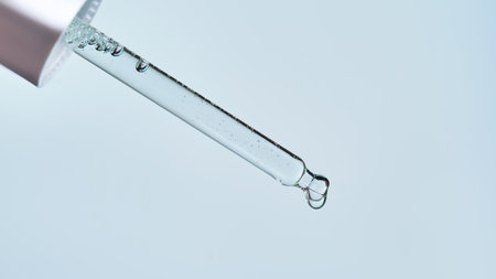 Pipette with serum on a blue background.