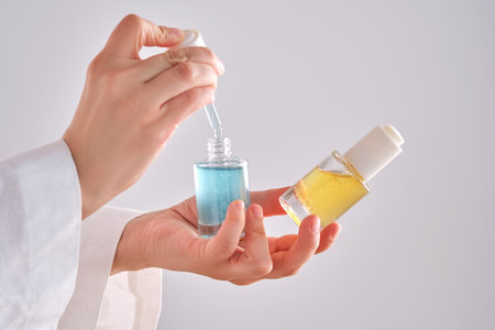 Two yellow and blue serums in a womans hands in a robe.
