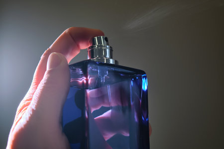 Perfume spray in a violet bottle on a dark background.