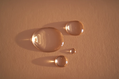 Beautiful volumetric drops of cosmetic product on a beige background.の写真素材