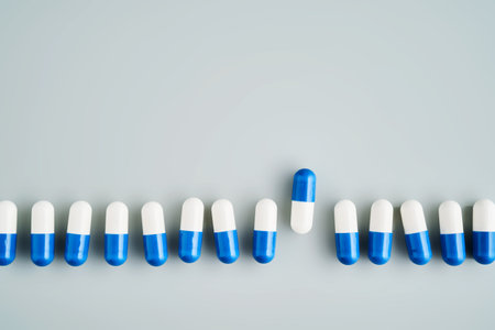 A row of white and blue pills on a blue background.の写真素材