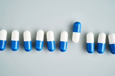 A row of white and blue pills on a blue background.の写真素材
