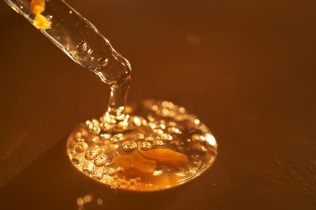 Pipette with serum shimmering in the sun on a beige background.の写真素材