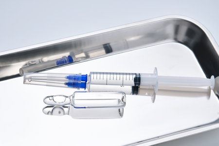 Syringes with needles and an ampoule in a stainless steel medical tray.の写真素材