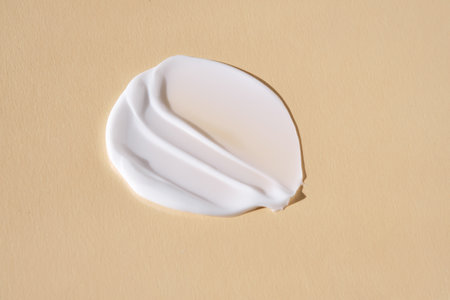 A smear of white cream on a beige background.