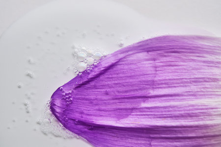A drop of serum on a purple flower petal.