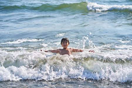 An 11 year old boy in having fun in the sea waves.の写真素材