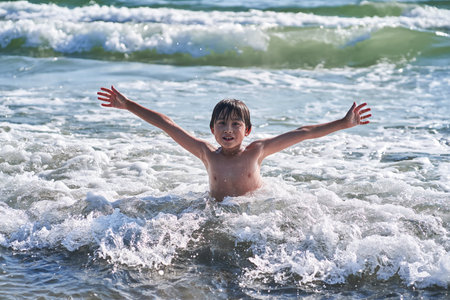 An 11 year old boy in having fun in the sea waves.の写真素材