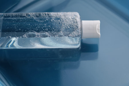 Bottle with cosmetic gel for face and body on blue background in water.