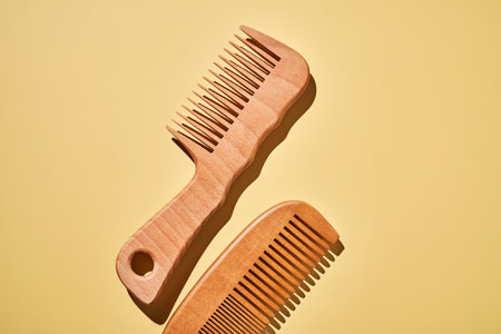 Two wooden combs on a yellow background.の写真素材