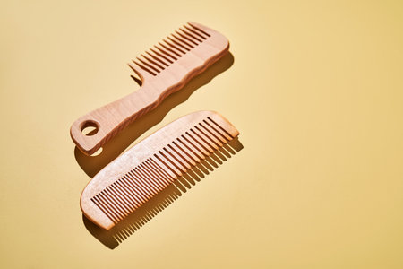 Two wooden combs on a yellow background.の写真素材