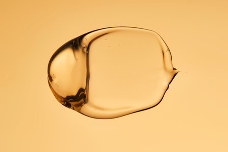 A beautiful drop of gel-like cosmetic serum with bubbles on a golden background.