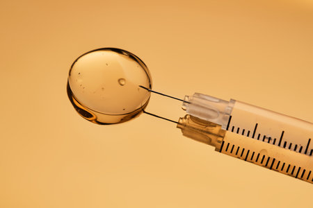 A drop of gel pours from a syringe for cosmetic procedures.