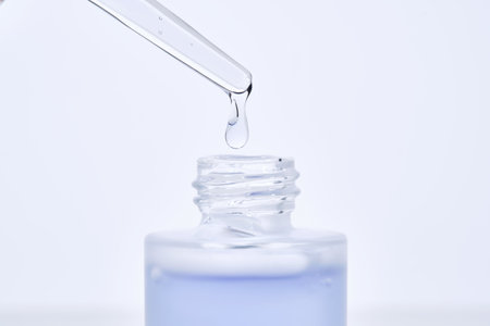 The blue serum drips from the dropper into the bottle.の写真素材