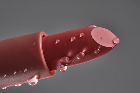 Classic lipstick with drops of water on a neutral background.の写真素材
