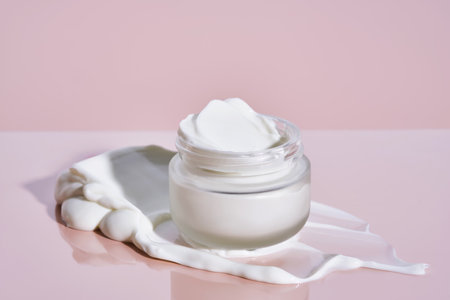 An open jar of cream with its texture on a pink background.の写真素材