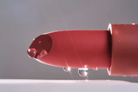 Classic lipstick with drops of water on a neutral background.の写真素材