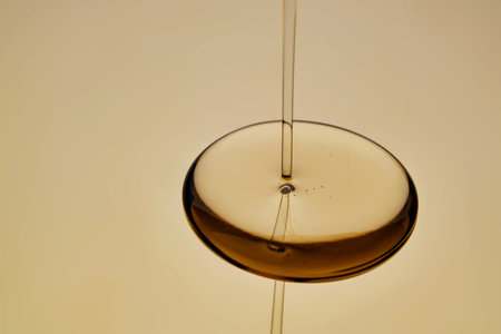 Texture of pouring cosmetic oil on a golden background.
