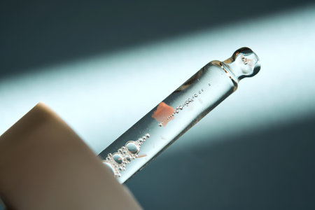 Pipette with serum on blue background with sunlight.の写真素材