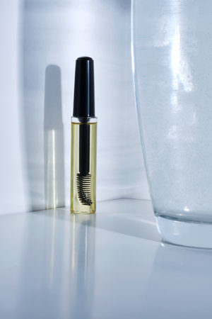 Bottle with brush filled with oil for eyebrow and eyelash growth.