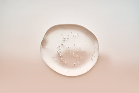 Textured drop of serum with bubbles on pink background.の写真素材