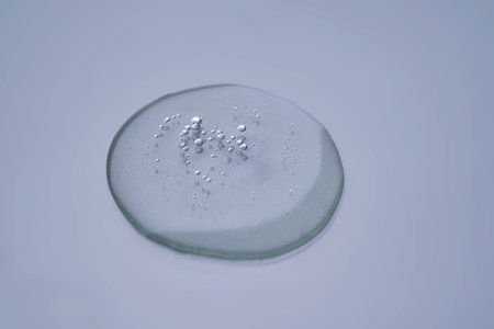 Textured round drop of serum with bubbles on dark blue background.の写真素材