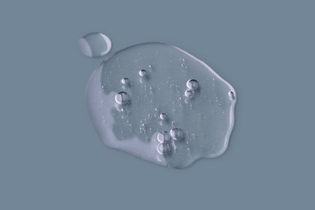 Textured round drop of serum with bubbles on dark blue background.