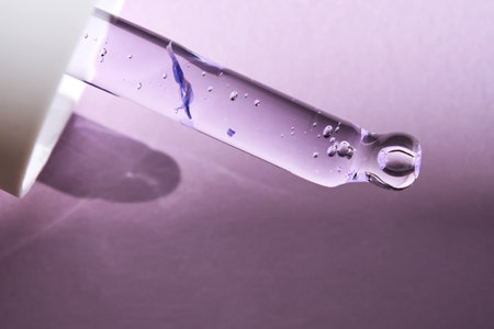 Pipette with serum on purple background with sunlight.の写真素材