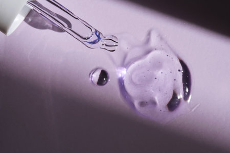 Pipette with serum on purple background with sunlight.
