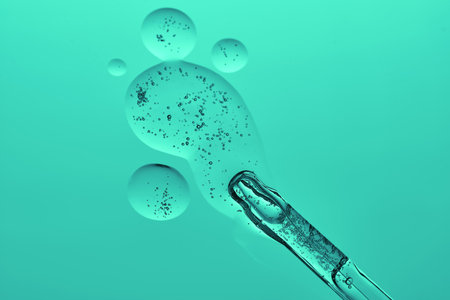 A dropper with a transparent serum texture on a green background.の写真素材