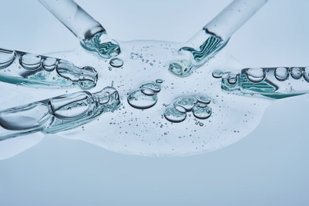 A large drop of hyaluronic serum and several pipettes on a blue background.の写真素材