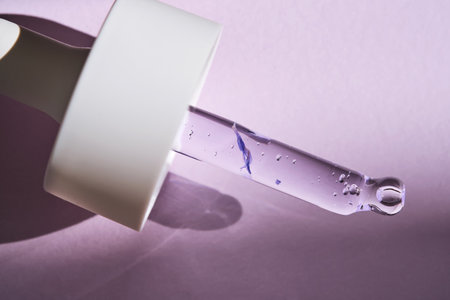Pipette with serum on purple background with sunlight.の写真素材