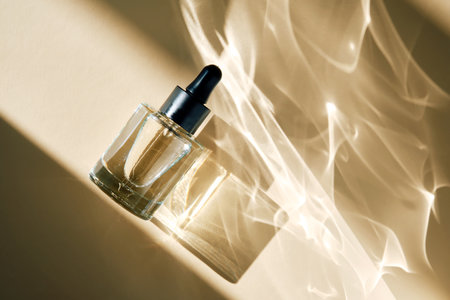 A bottle of facial oil on a beige background with beautiful highlights.の写真素材