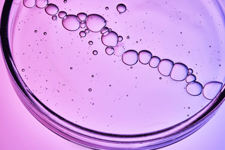 The texture of a cosmetic serum with a trail of bubbles on a purple background.