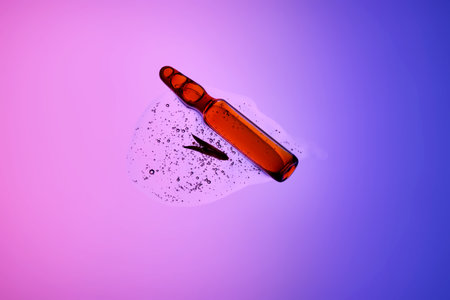 An ampoule with serum in its texture on a purple background with a leaf.の写真素材