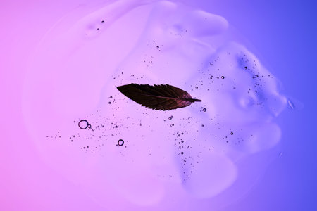 Beautiful texture of gel-like serum with a leaf on a purple background.